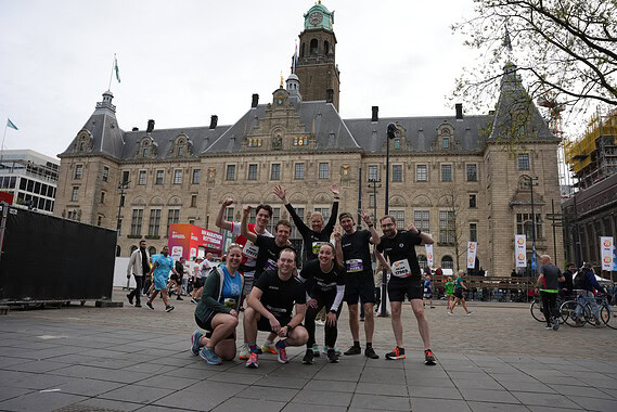 Active group of marathon runners celebrating in front of historic city hall during a corporate team-building event.