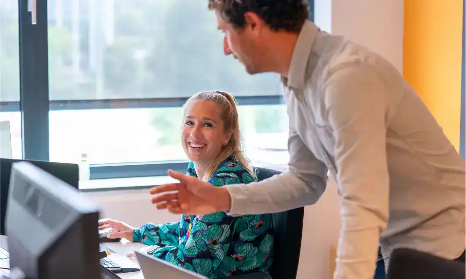 Professional woman smiling at her desk in an office environment.