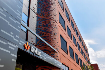 Innovative Keylane office building architecture, modern brick facade with dark window accents, serving as a dynamic workspace aimed at fostering career growth in the tech and insurance industries.