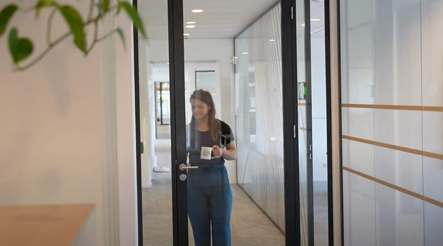 Careers at Keylane modern office building with employee entering through glass door, focusing on Keylane's innovative work environment and recruitment opportunities in financial technology.