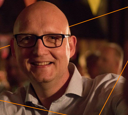 Friendly, professional man smiling at networking event, representing career growth opportunities at Keylane with a focus on innovative insurance tech careers.