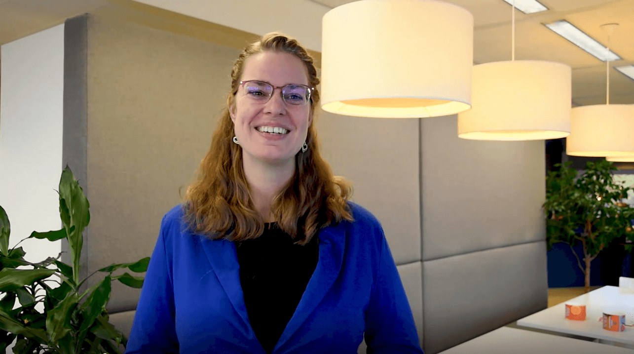 Confident woman smiling in modern office environment, representing careers at Keylane in insurance and finance tech industry.