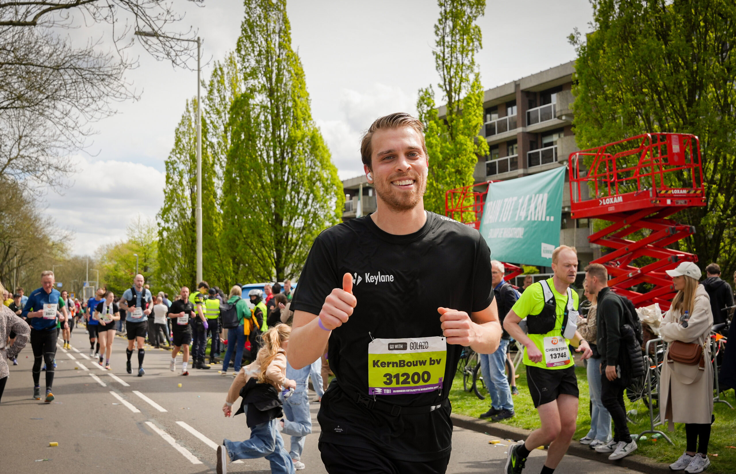 Active man running in marathon event, Keylane branded runner participating in race, vibrant outdoor marathon scene with supporters and runners, promoting health and corporate team spirit.