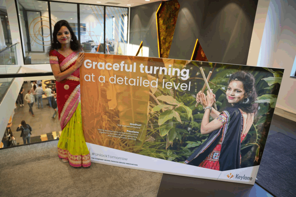 Graceful Indian woman in traditional attire holding a Keylane Career event sign at corporate office.