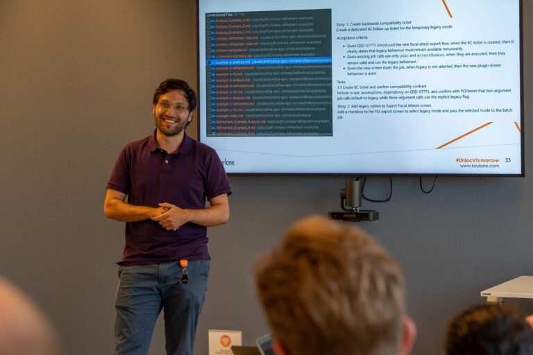 Man giving a presentation at Keylane AI Hackathon event, with a large screen displaying code and instructions behind him.